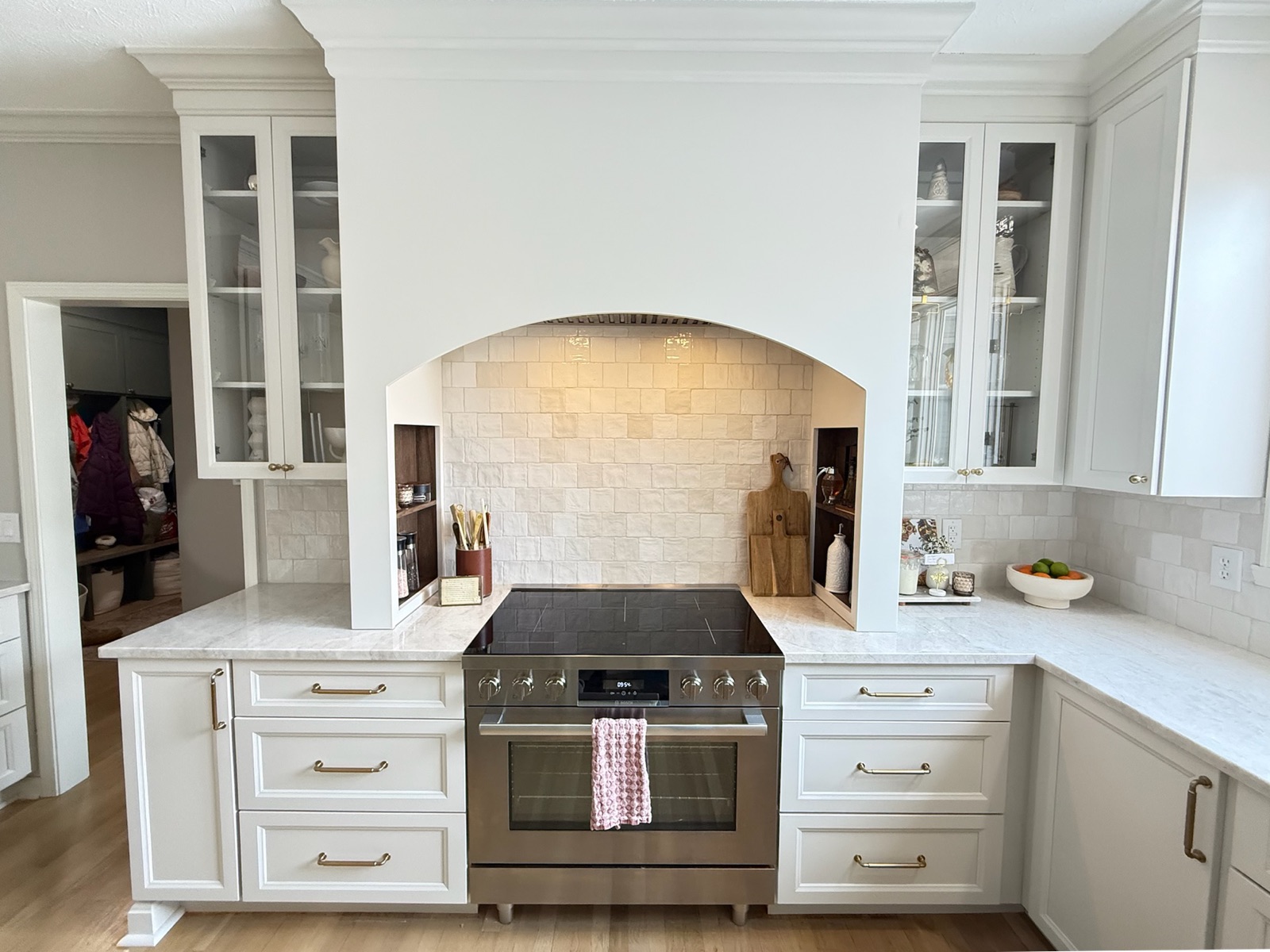 Arched range alcove with handmade zellige tile backsplash, stainless range, and built-in spice niches